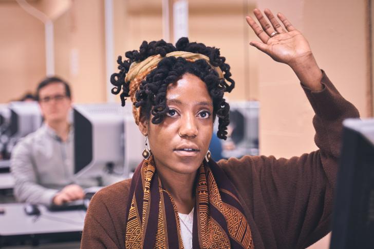 person raising hand in computer lab