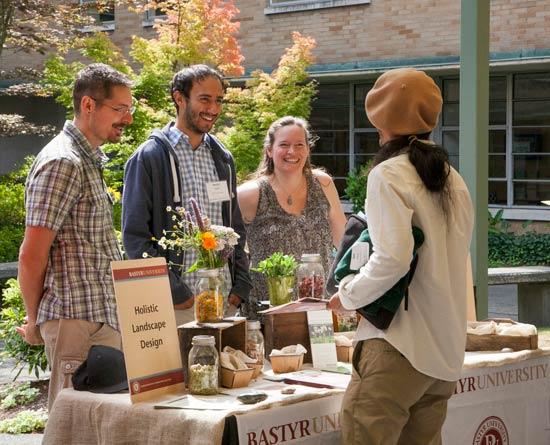 four people standing around a bastyr booth table