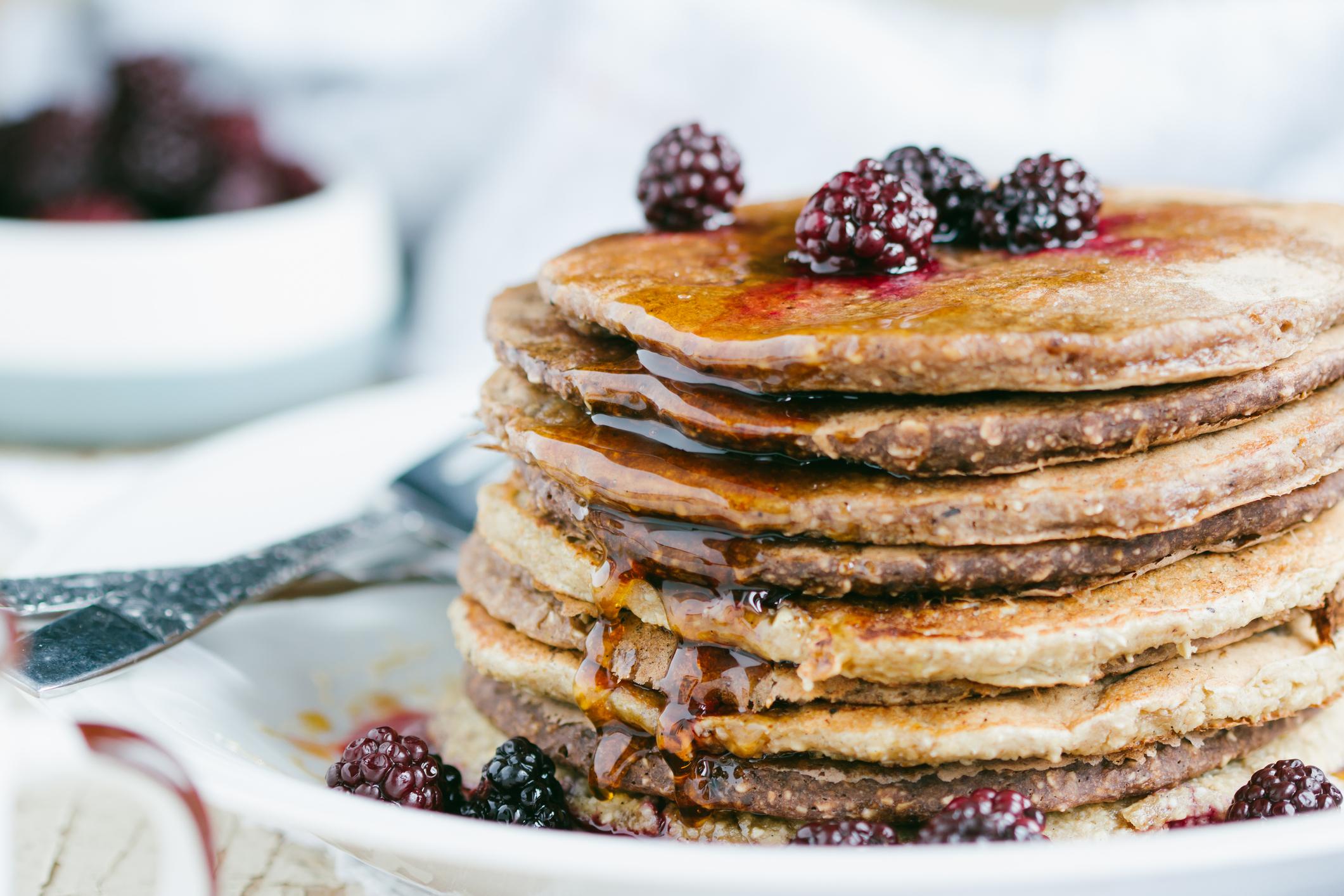stack of oat pancakes with syrup and fruit
