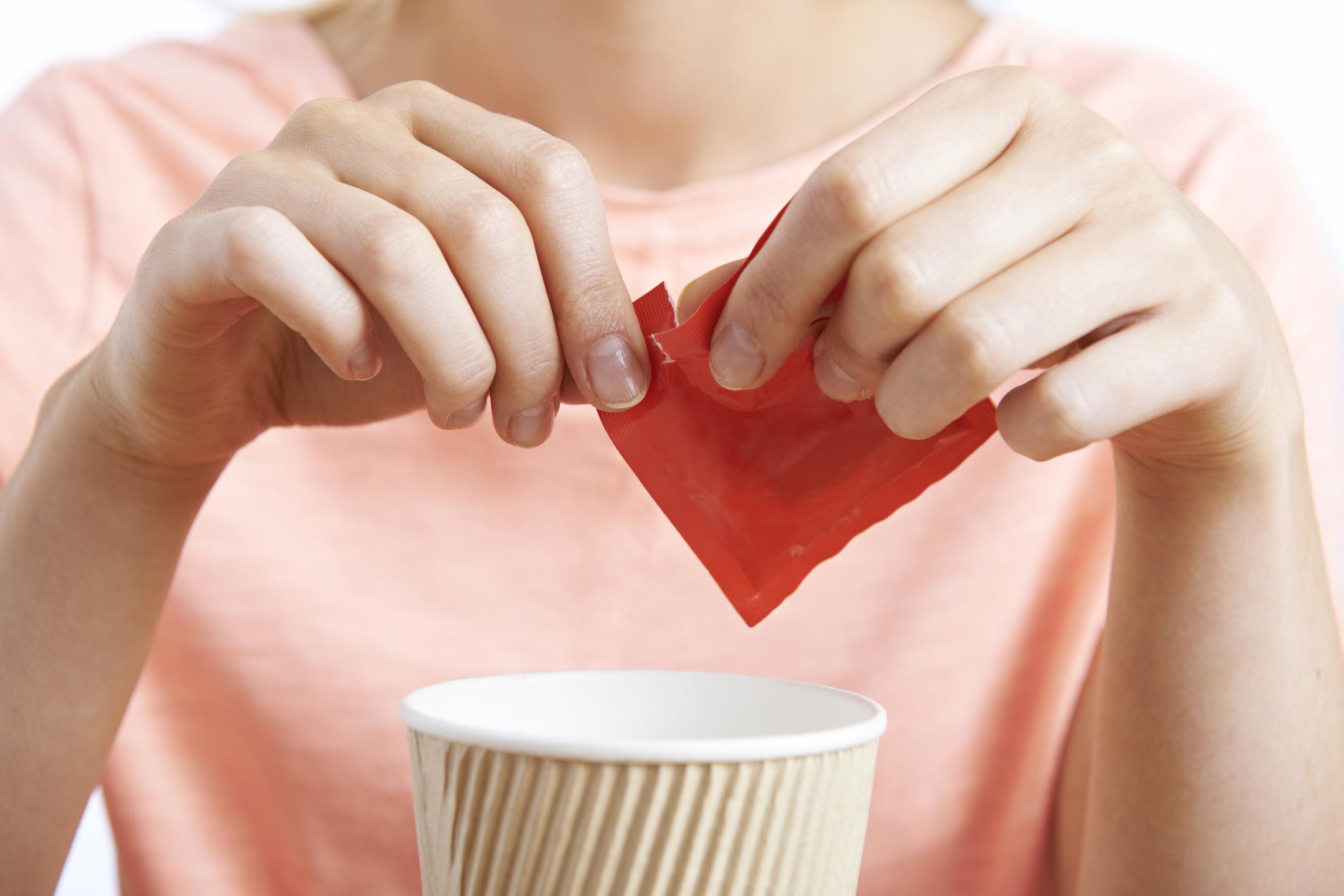 person tearing open red package over a paper cup
