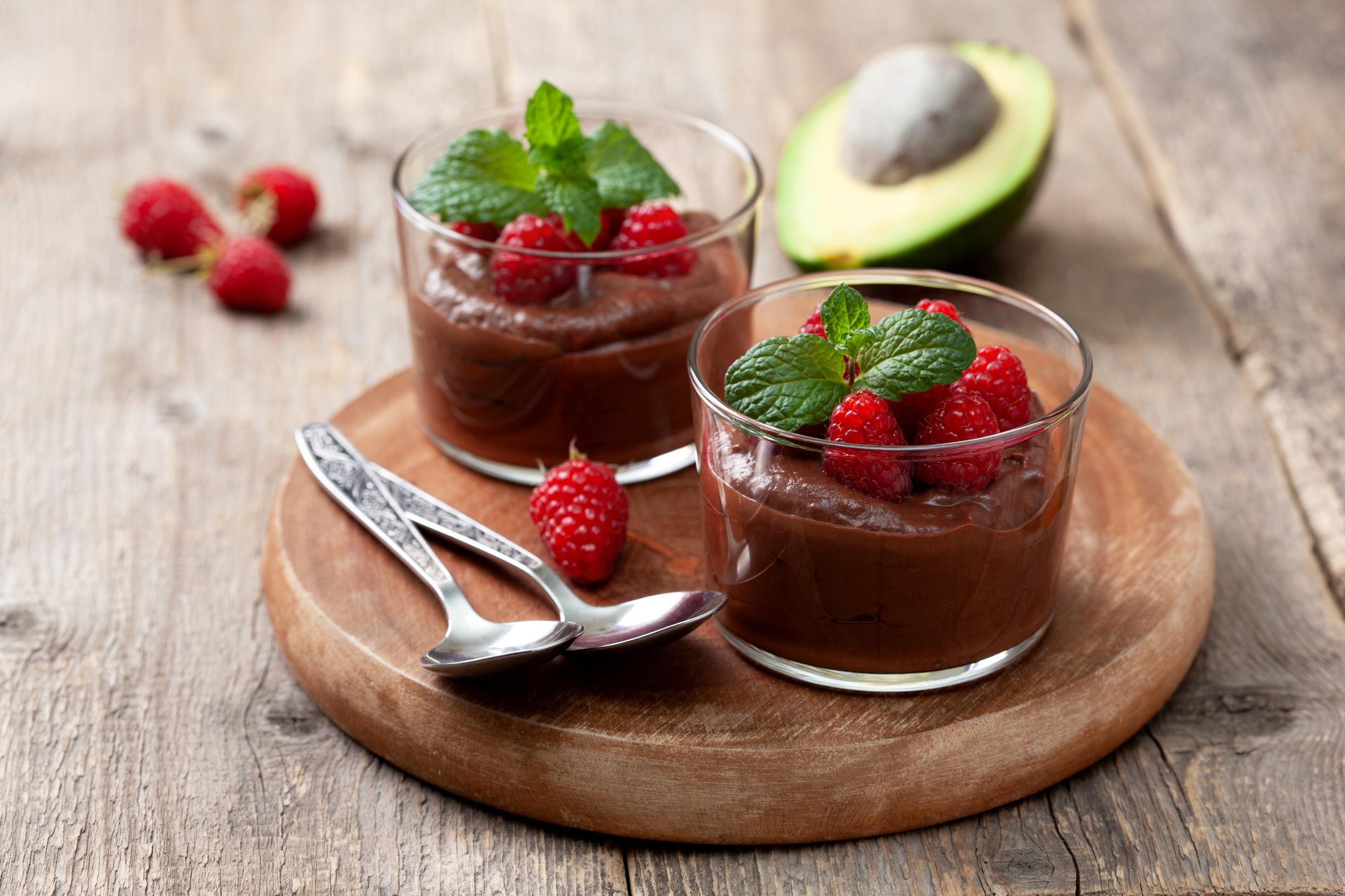 two cups on chocolate mousse with raspberries and an avocado