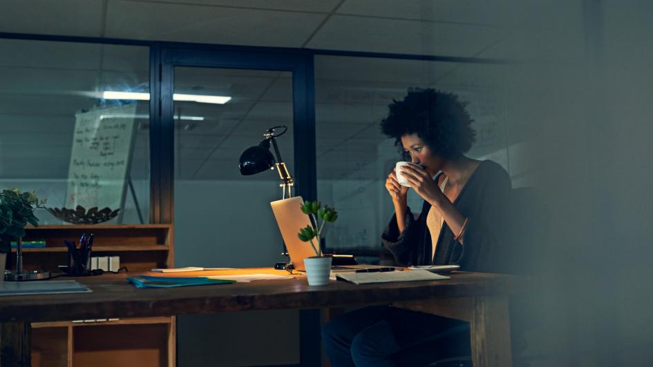 person at desk drinking from cup