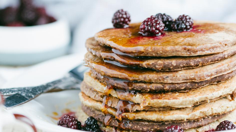 stack of oat pancakes with syrup and fruit