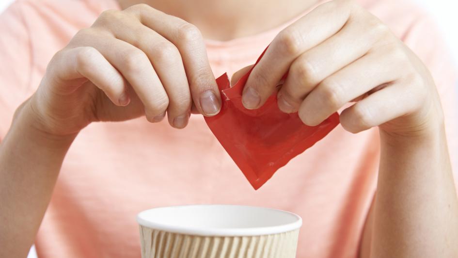 person tearing open red package over a paper cup