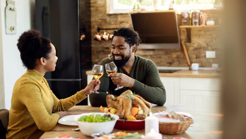 couple toasting wine glasses sitting at a table