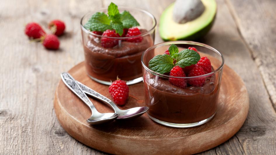 two cups on chocolate mousse with raspberries and an avocado