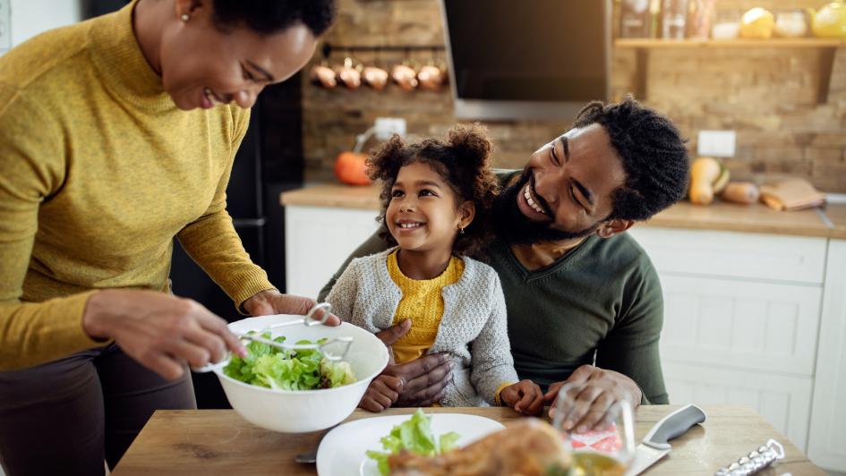 person serving salad to another person with a child in their lap