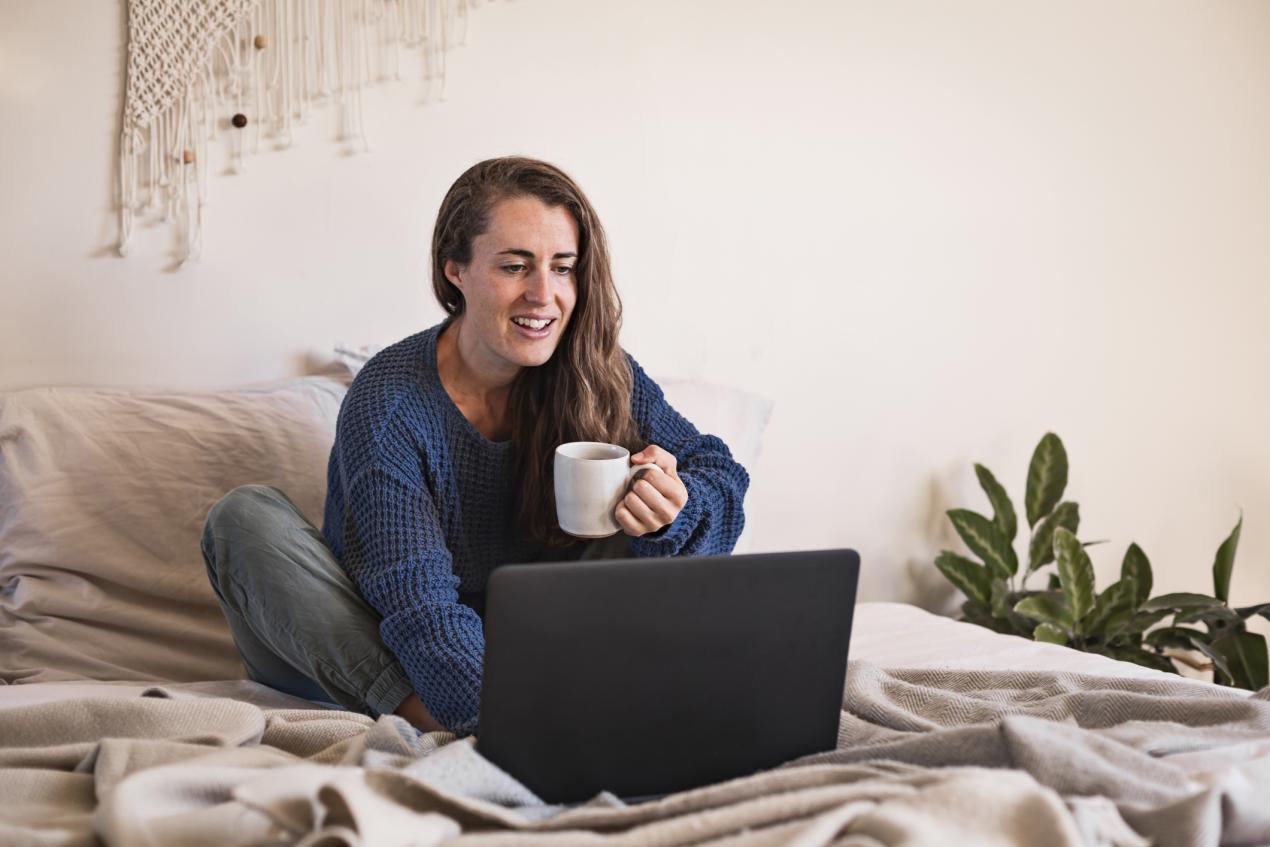 student talking on laptop on dorm bed